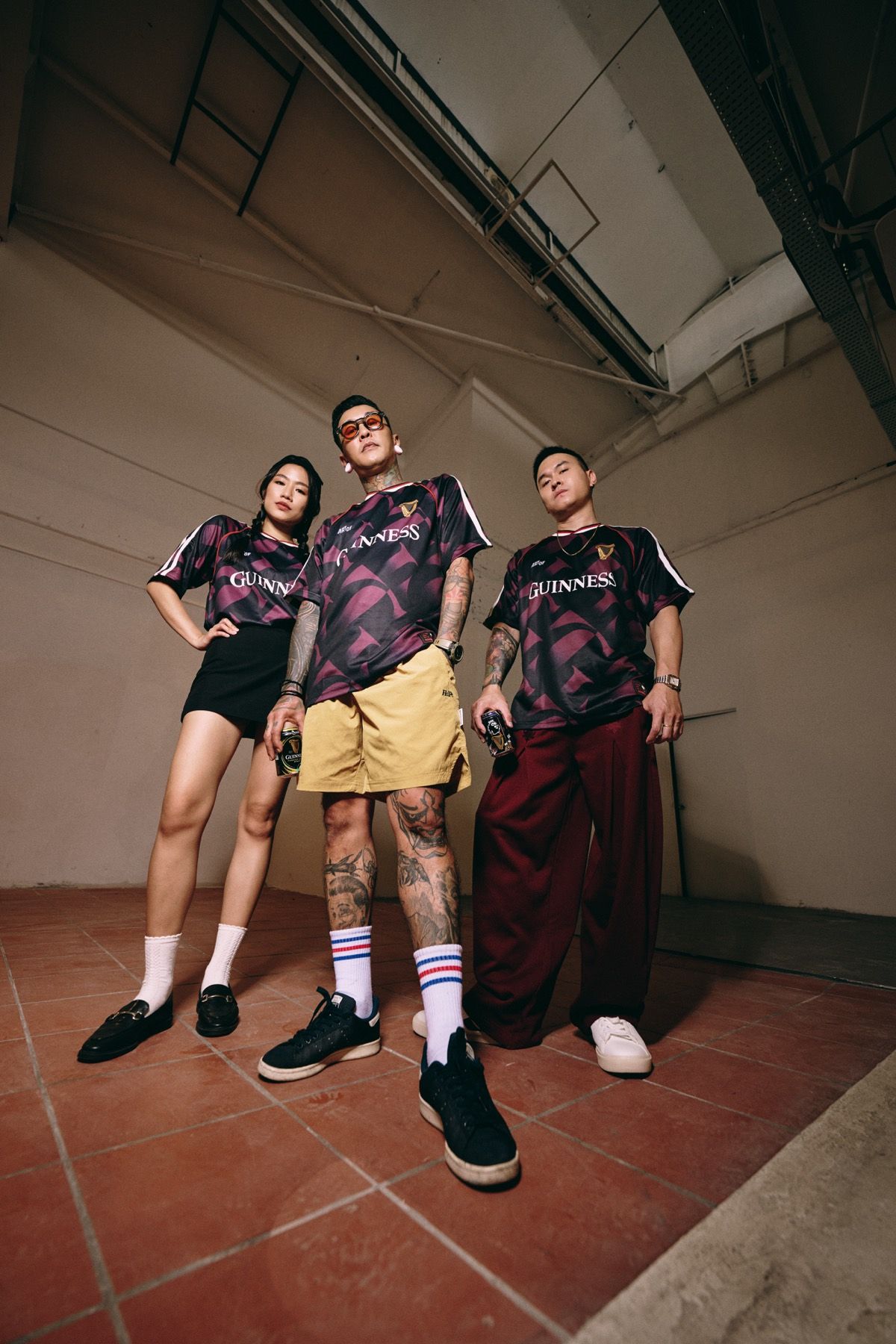 Three models posed in a warehouse with a brick wall