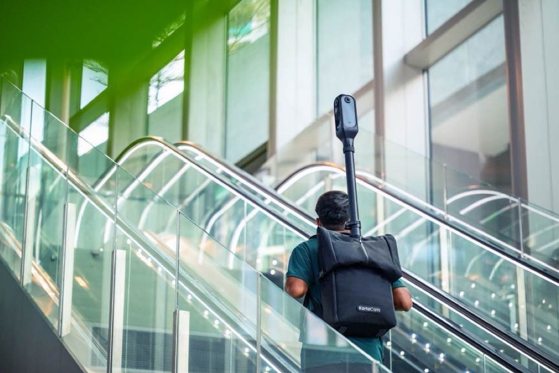 A mapper riding an escalator with the camera on his backpack