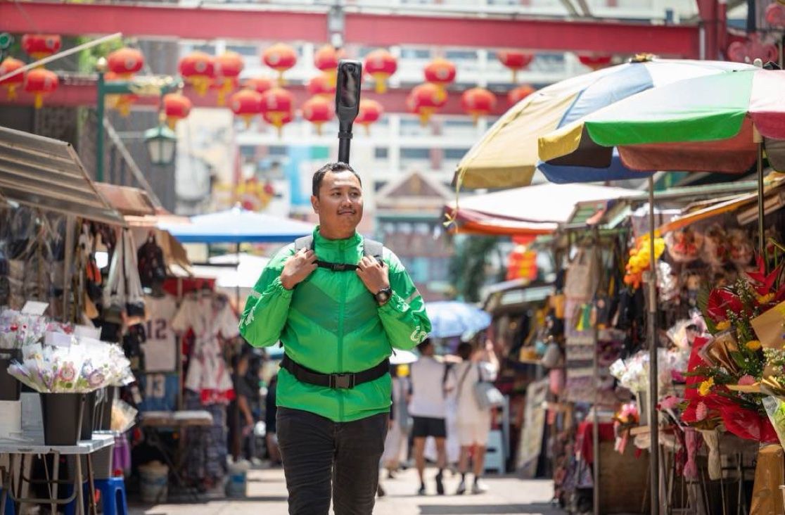 A mapper walking through the market under umbrellas and lanterns