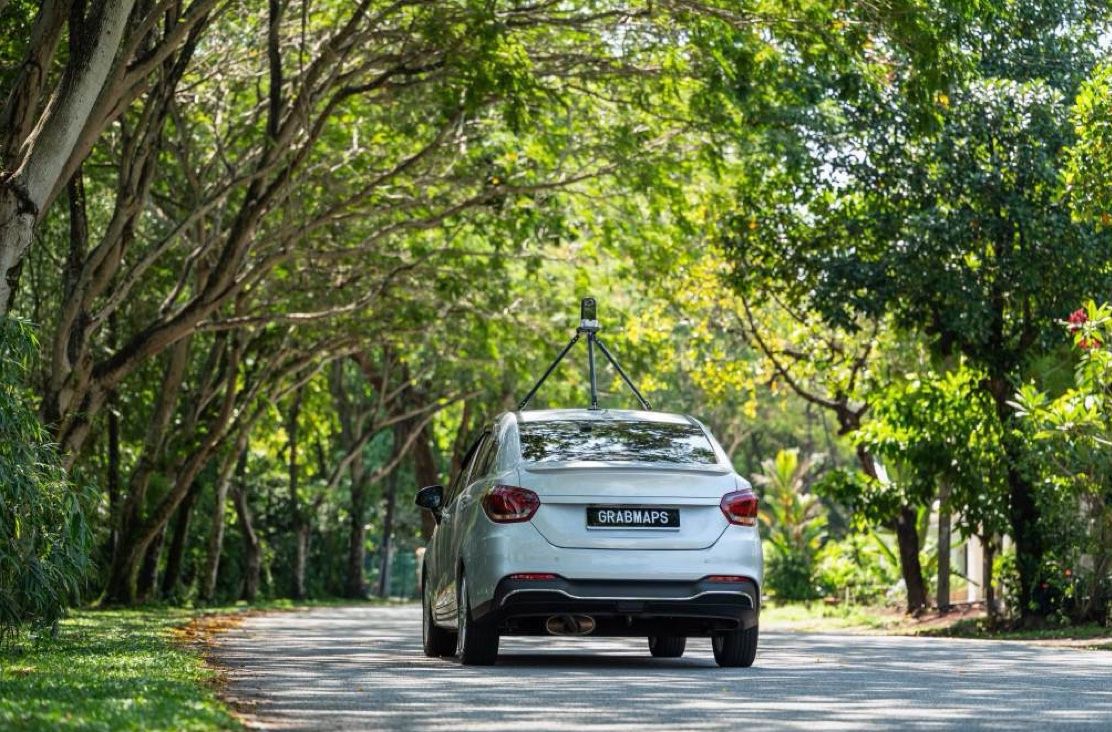 A mapping car on a road under a tree canopy