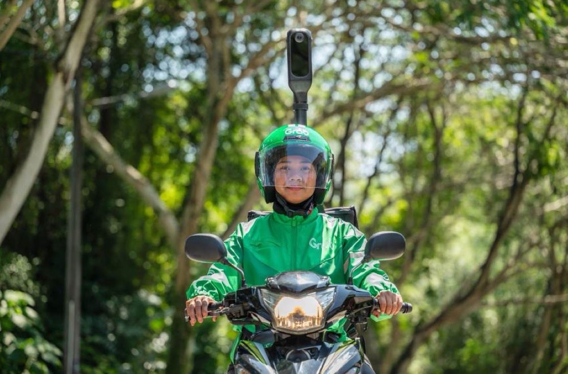 A rider on a scooter between tall trees