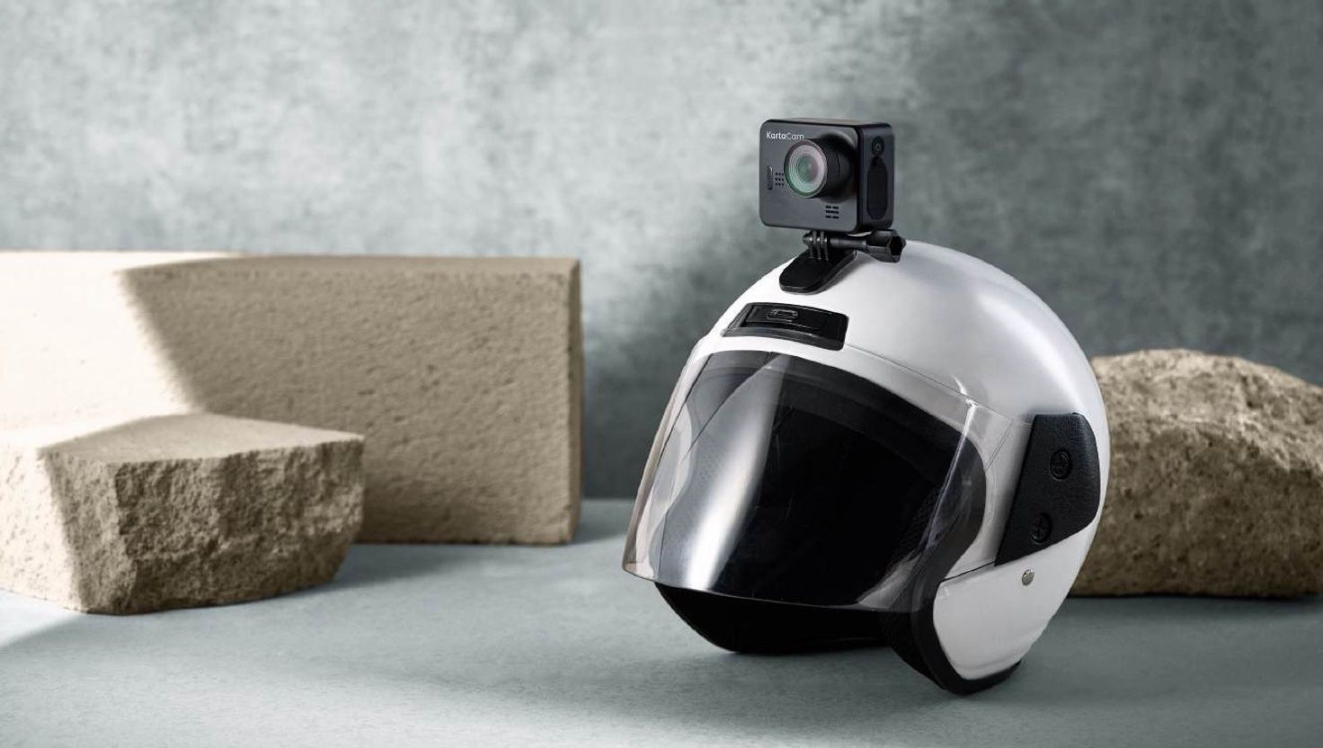 KartaCam 1st edition mounted on a white motorcycle helmet among stone blocks