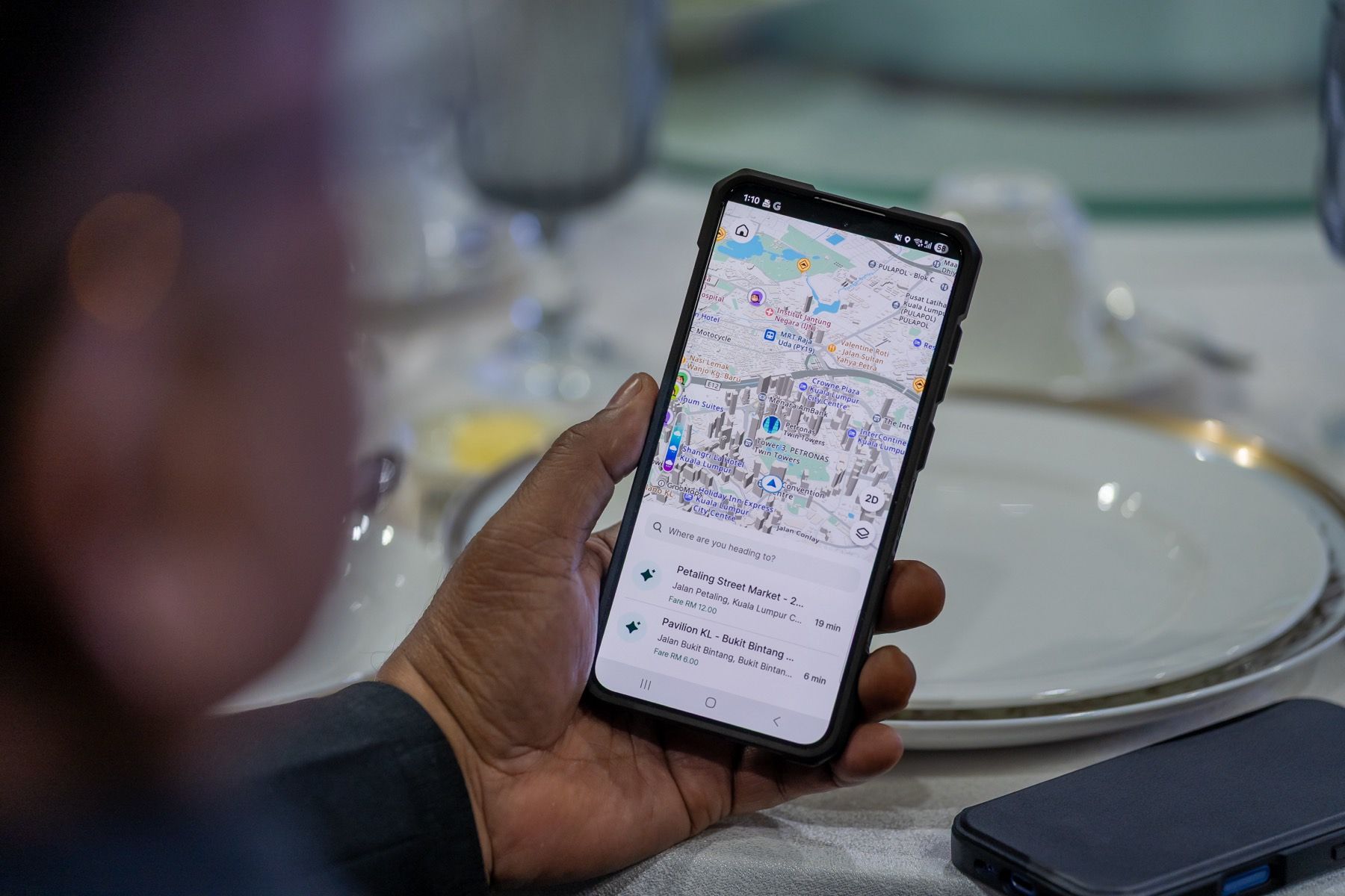 A hand holding a phone showing the GrabMaps app