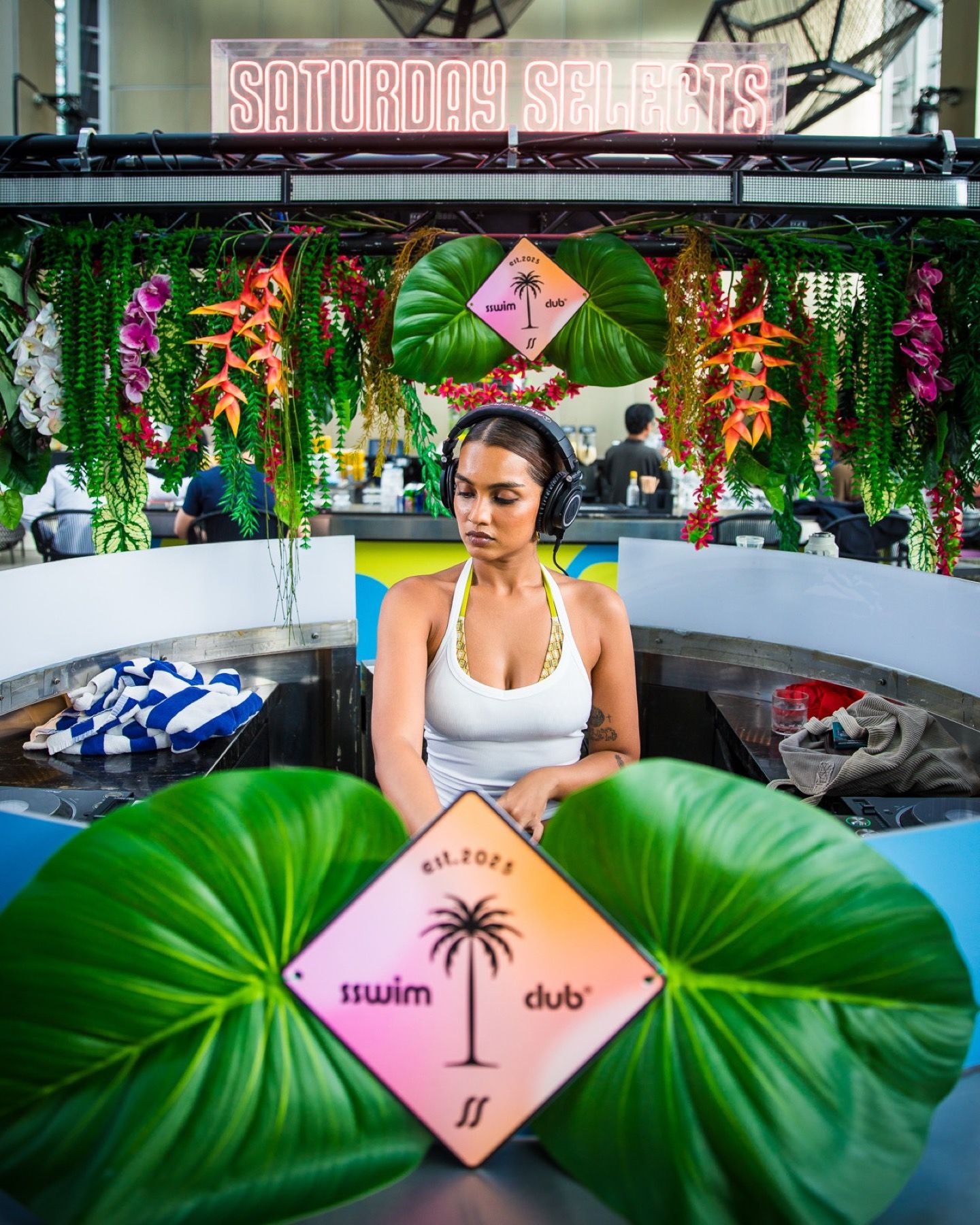 A guest at the booth framed by leaves and the Swwim Club sign
